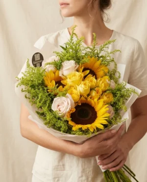 Ramo de girasoles con rosas amarillas y rosas envuelto en papel blanco