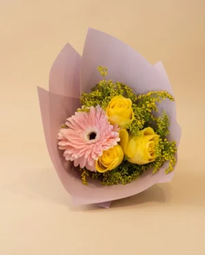 Ramo de rosas amarillas y gerbera rosa envuelto en papel coreano