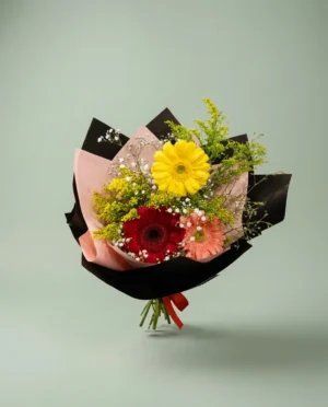 Ramo de gerberas multicolor envuelto en tonos oscuros con detalles florales